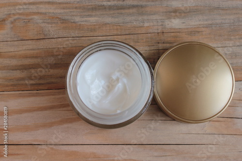 A jar with cosmetic cream stands on a wooden background.