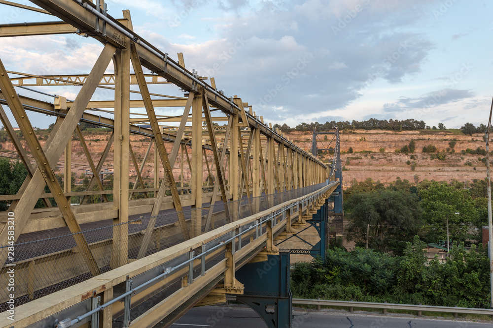 Angled view down large steel bridge crossing over river with mountain Angled view down large steel bridge crossing over river with mountain