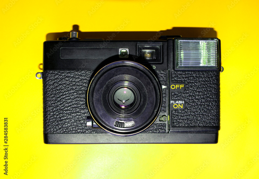 Old black vintage film camera isolated on yellow background, close up 