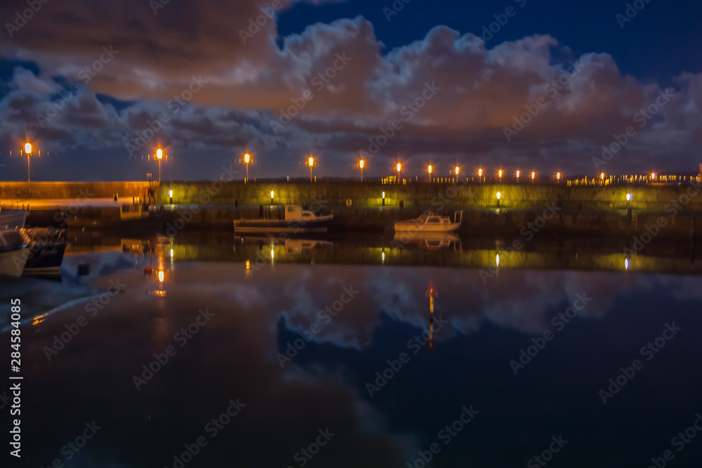 Night view of Carrickfergus Harbour with reflections of clouds in the water