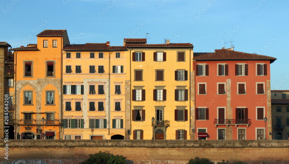 Historical apartment house facades in Pisa, Italy, at sunset