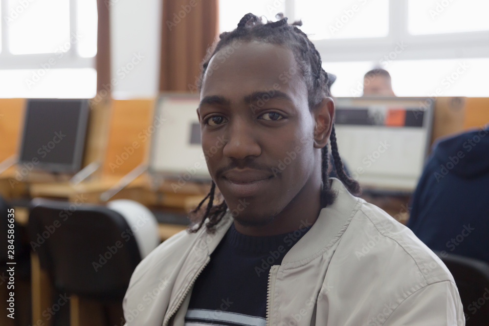 Naklejka premium University mixed race Students, african, american and european during the class in computer room. Resolving problems together. African student looking into camera.