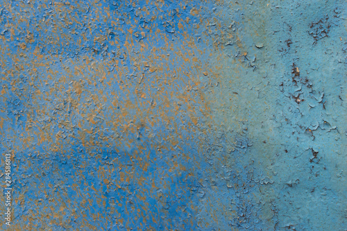 a rusty metal surface painted with peeling and cracked with blue paint as an abstract background