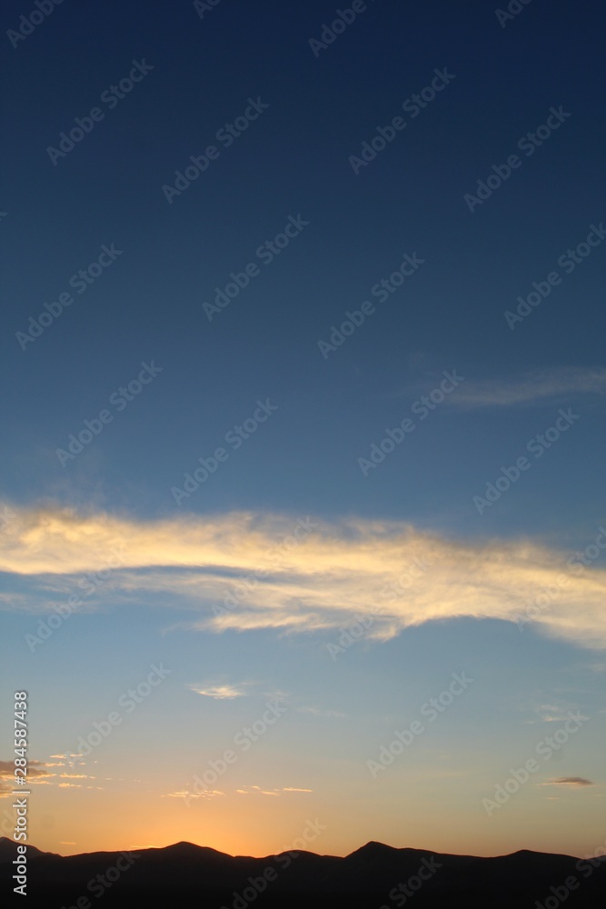 Fototapeta premium Heavens illuminate as sun sets over the Hexie Mountains of Joshua Tree National Park. Although much of the range is within the Mojave, its edges transition and integrate with the Colorado Desert.
