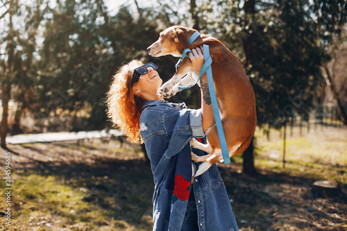 Beautiful girl in a park. Stylish woman in a jeans jacket. Ladies with a dog photo