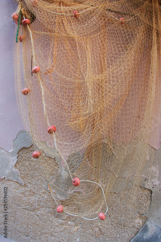 The fishing net hangs on the wall. Part of the facade on the wall is missing.