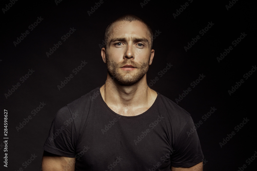 Muscle strong beautiful stripped male model with black t-shirt in denim blue jeans on black isolated font background