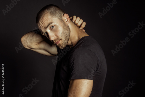 Muscle strong beautiful stripped male model with black t-shirt in denim blue jeans on black isolated font background © Oleh Phoenix