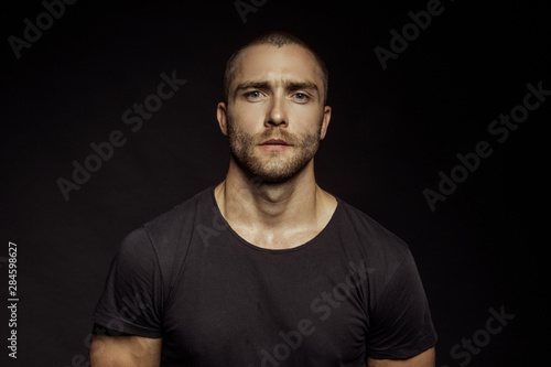 Muscle strong beautiful stripped male model with black t-shirt in denim blue jeans on black isolated font background photo