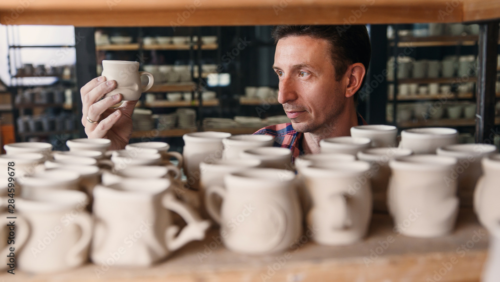 Focused man looking to the handmade cap in the pottery. Focused man looking to the handmade cap in the pottery.