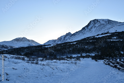 winter alpine meadow with sunrise and mountains in the background