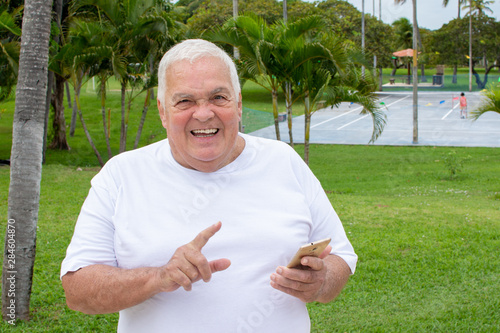 Fat old man searches with cellphone use in nature (mobile phone)