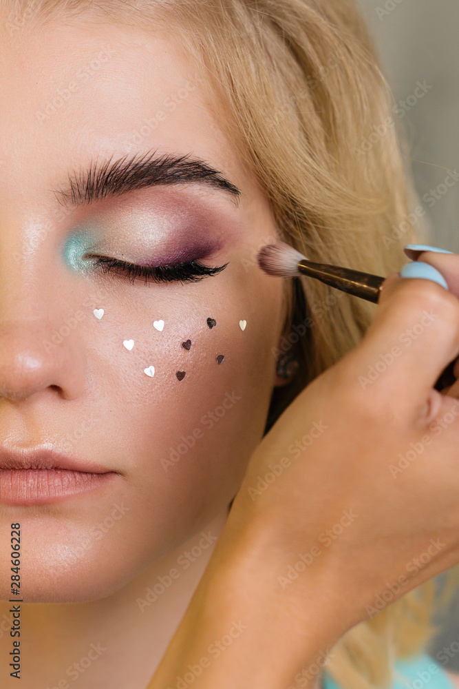 Makeup artist applies eye shadow on moving eyelid model. Creative makeup. Beauty industry. Beauty salon concept