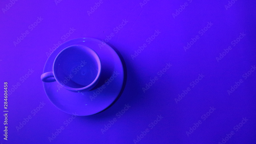 Cup of tea, coffee below neon light. With copy space to insert text. Wide screen view. It represents youth which works and have to be profitable Cup of tea, coffee below neon light. With copy space to insert text. Wide screen view. It represents youth which works and have to be profitable