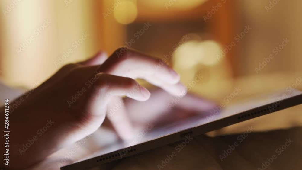 Hand of kid girl touchscreen on modern digital tablet on bedroom in night time Hand of kid girl touchscreen on modern digital tablet on bedroom in night time