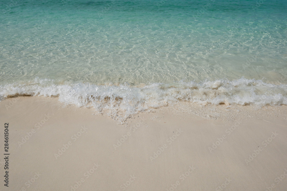 crystal clear Andaman blue sea with white waving and smooth sand beach in bright daylight