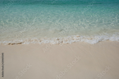 crystal clear Andaman blue sea with white waving and smooth sand beach in bright daylight