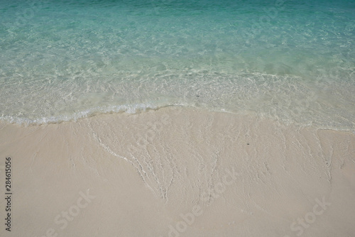 crystal clear Andaman blue sea with white light waving and smooth sand beach in bright daylight
