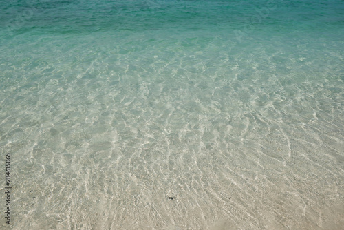 crystal clear Andaman blue sea with smooth curve of water and sand beach beneath it in bright daylight