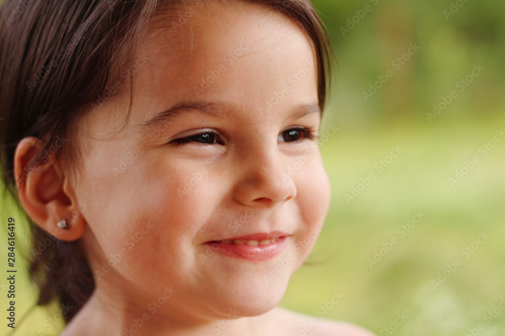 portrait of a cute little cheerful girl in the park outdoors
