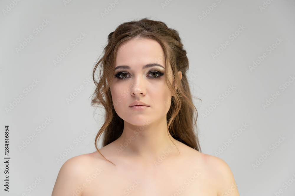 Close-up photo portrait of a pretty brunette woman girl with long beautiful curly hair on a white background. Standing in front of the camera Close-up photo portrait of a pretty brunette woman girl with long beautiful curly hair on a white background. Standing in front of the camera
