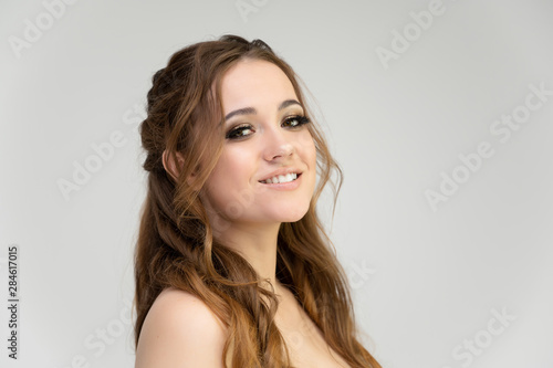Close-up photo portrait of a pretty brunette woman girl with long beautiful curly hair on a white background. Standing in front of the camera © Вячеслав Чичаев