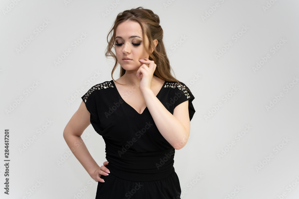 Photo waist-length portrait of a pretty brunette woman girl with long beautiful curly hair on a white background in a black dress. Talking in different poses. Standing facing the camera. Photo waist-length portrait of a pretty brunette woman girl with long beautiful curly hair on a white background in a black dress. Talking in different poses. Standing facing the camera.