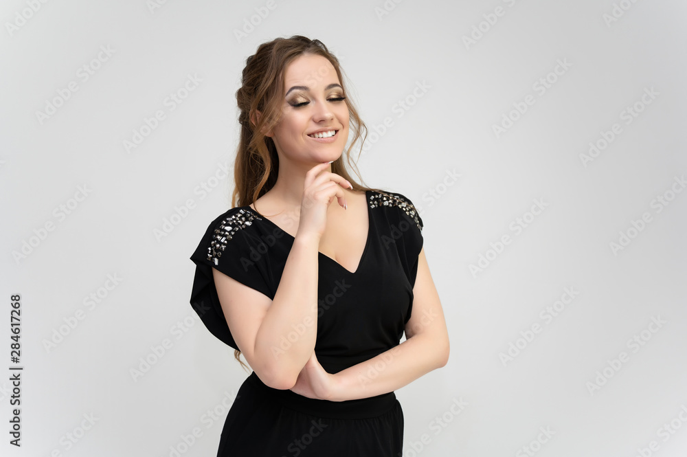 Photo waist-length portrait of a pretty brunette woman girl with long beautiful curly hair on a white background in a black dress. Talking in different poses. Standing facing the camera. Photo waist-length portrait of a pretty brunette woman girl with long beautiful curly hair on a white background in a black dress. Talking in different poses. Standing facing the camera.