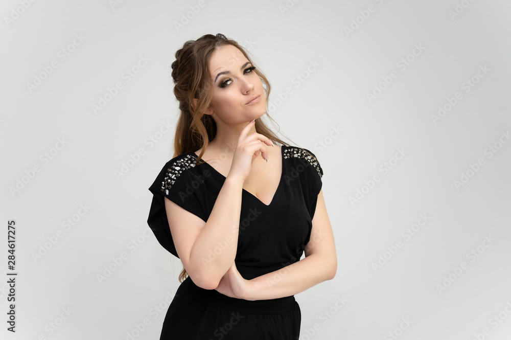 Photo waist-length portrait of a pretty brunette woman girl with long beautiful curly hair on a white background in a black dress. Talking in different poses. Standing facing the camera. Photo waist-length portrait of a pretty brunette woman girl with long beautiful curly hair on a white background in a black dress. Talking in different poses. Standing facing the camera.