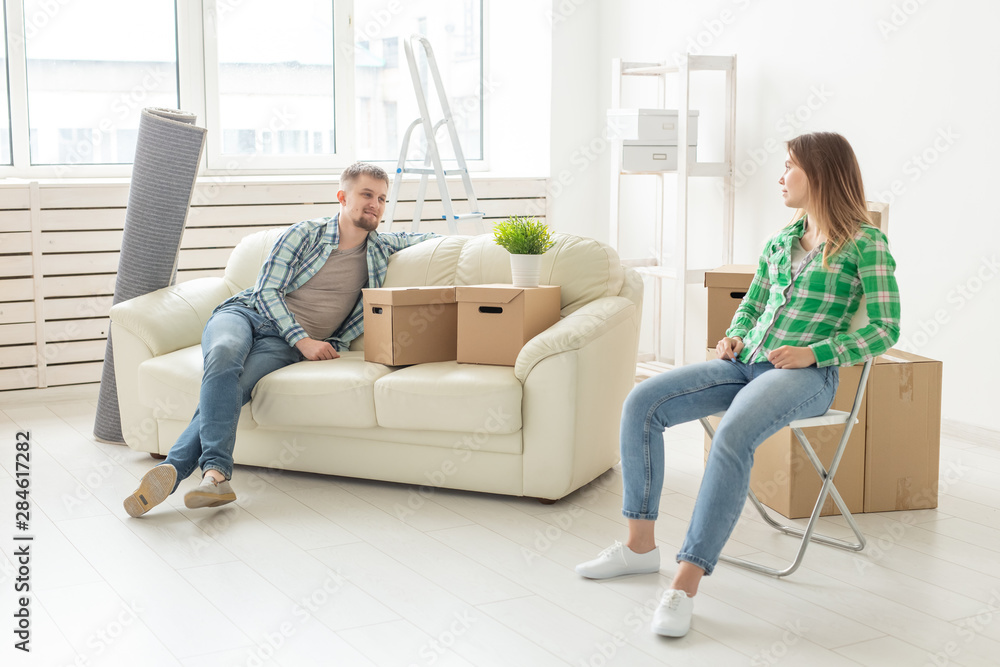 Positive smiling young girl sitting against her laughing in a new living room while moving to a new home. The concept of joy from the possibility of finding new housing. Positive smiling young girl sitting against her laughing in a new living room while moving to a new home. The concept of joy from the possibility of finding new housing.