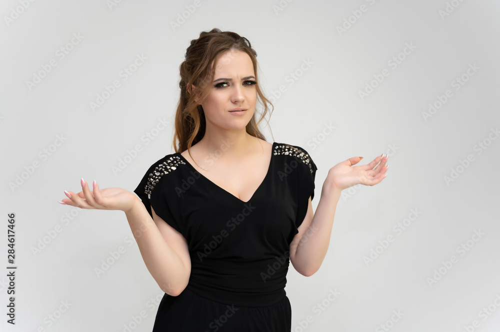 Photo waist-length portrait of a pretty brunette woman girl with long beautiful curly hair on a white background in a black dress. Talking in different poses. Standing facing the camera. Photo waist-length portrait of a pretty brunette woman girl with long beautiful curly hair on a white background in a black dress. Talking in different poses. Standing facing the camera.