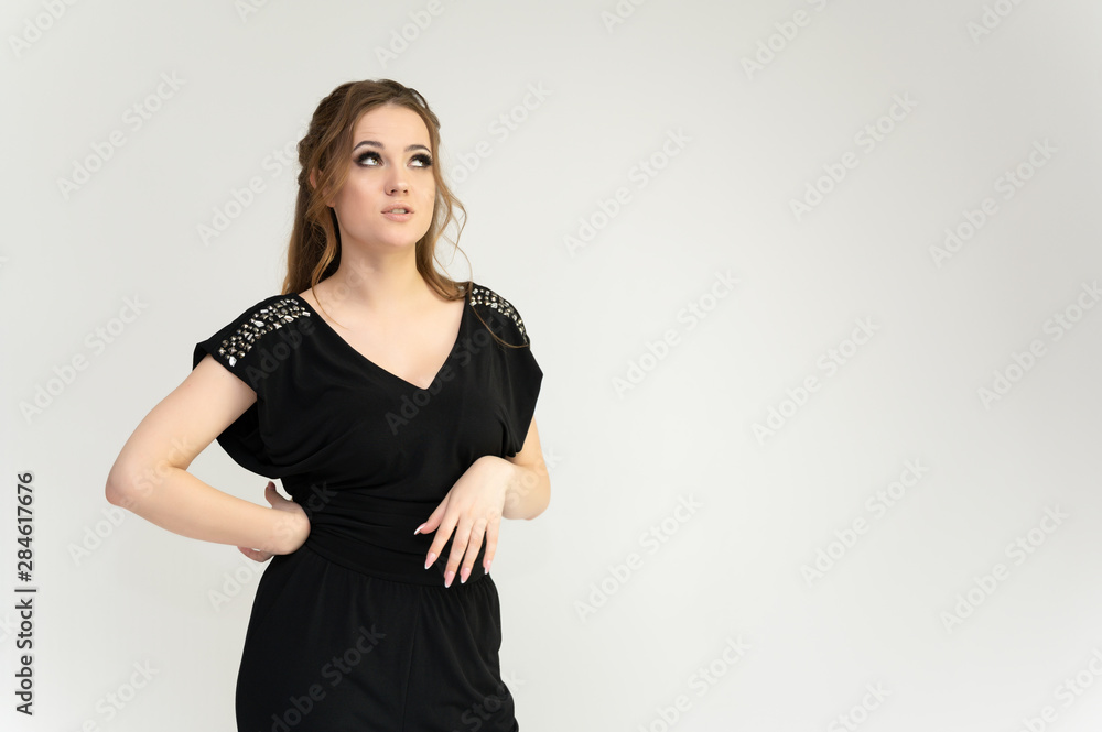 Photo waist-length portrait of a pretty brunette woman girl with long beautiful curly hair on a white background in a black dress. Talking in different poses. Standing facing the camera. Photo waist-length portrait of a pretty brunette woman girl with long beautiful curly hair on a white background in a black dress. Talking in different poses. Standing facing the camera.