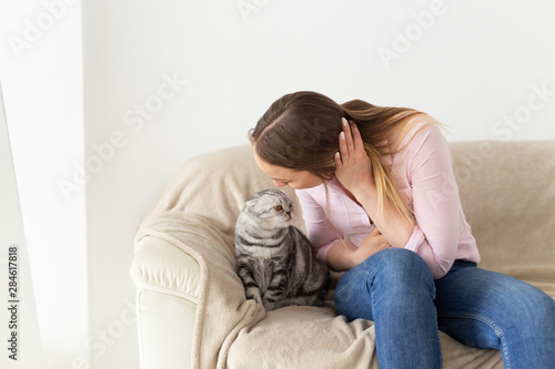 Woman at home kissing her lovely fluffy cat. Gray tabby cute scottish fold cat. Pets and lifestyle concept.