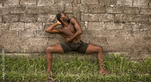 young attractive contemporary ballet dancer and choreographer , a black afro American man dancing and posing on tropical rice field background