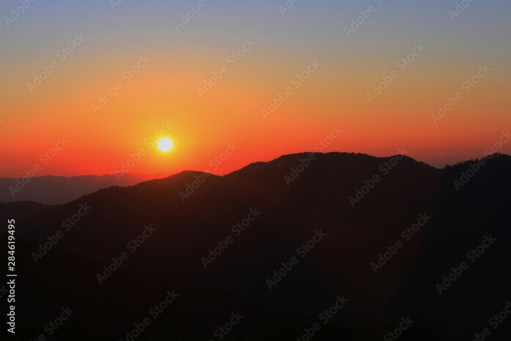 Sunset in sky and cloud, beautiful colorful twilight time with silhouette of mountain.