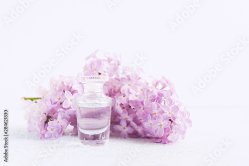 Perfume of lilac in glass bottle on white background. Soft focus with copy space