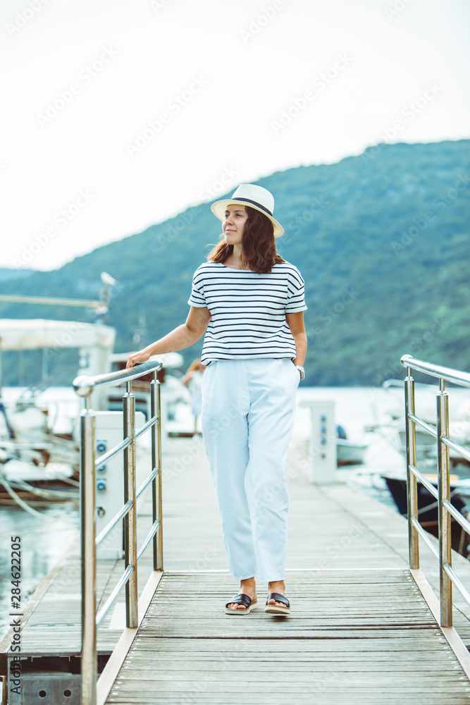 woman in white fashion luxury view walking by dock boats on background