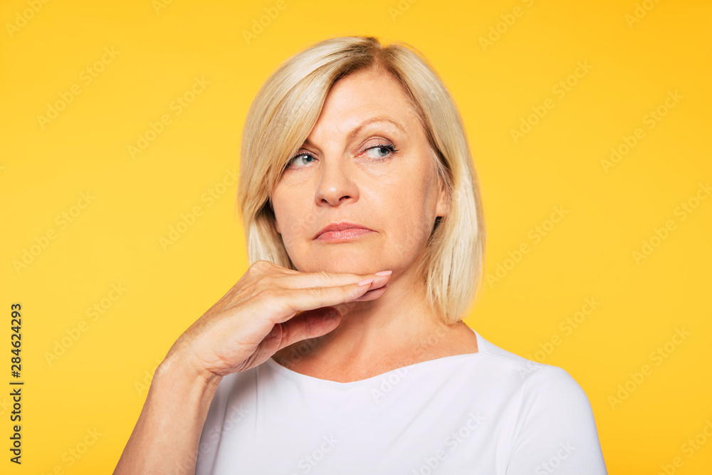 Happy smiling beautiful cute lovely blonde senior woman with beauty clean skin in casual wear isolated on yellow background. Healthcare and cosmetology concepts. Pensioner and mature people Happy smiling beautiful cute lovely blonde senior woman with beauty clean skin in casual wear isolated on yellow background. Healthcare and cosmetology concepts. Pensioner and mature people