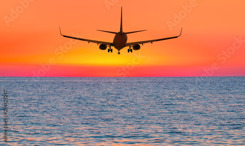 Airplane flying above tropical sea at sunset © muratart