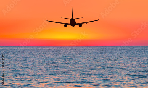 Airplane flying above tropical sea at sunset © muratart