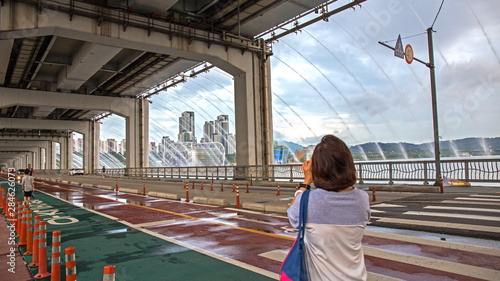 Photography a woman taking a photo with mobile phone during the Hanpo bridge fountain show