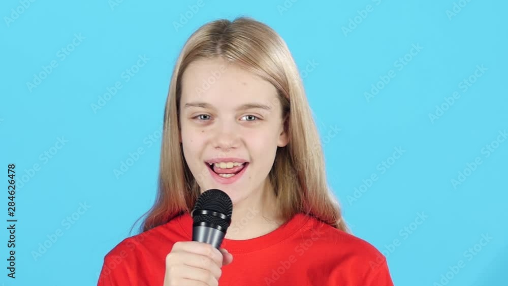 Close-up little girl who smiling and singing with microphone. Slow motion Close-up little girl who smiling and singing with microphone. Slow motion