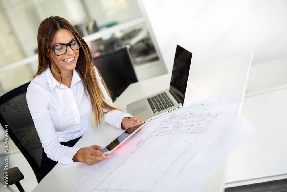 Young female architect working with computer and blueprints Young female architect working with computer and blueprints