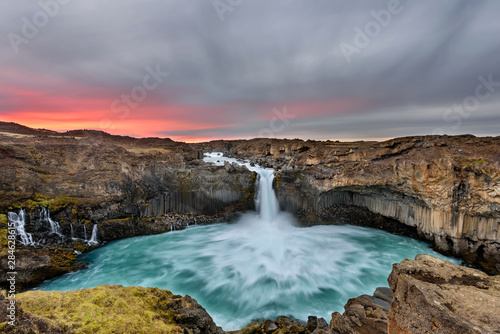 Aldeyjarfoss waterfall in Iceland at sunrise with golden clouds in the sky. Amazing landscape in beautiful tourist attraction. Wonder of nature with glacier water.