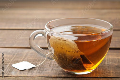 Tea bag in a glass cup on a brown wooden background. to make tea