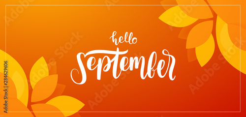 Autumn background with handwritten lettering of Hello September with fall leaves on orange background photo