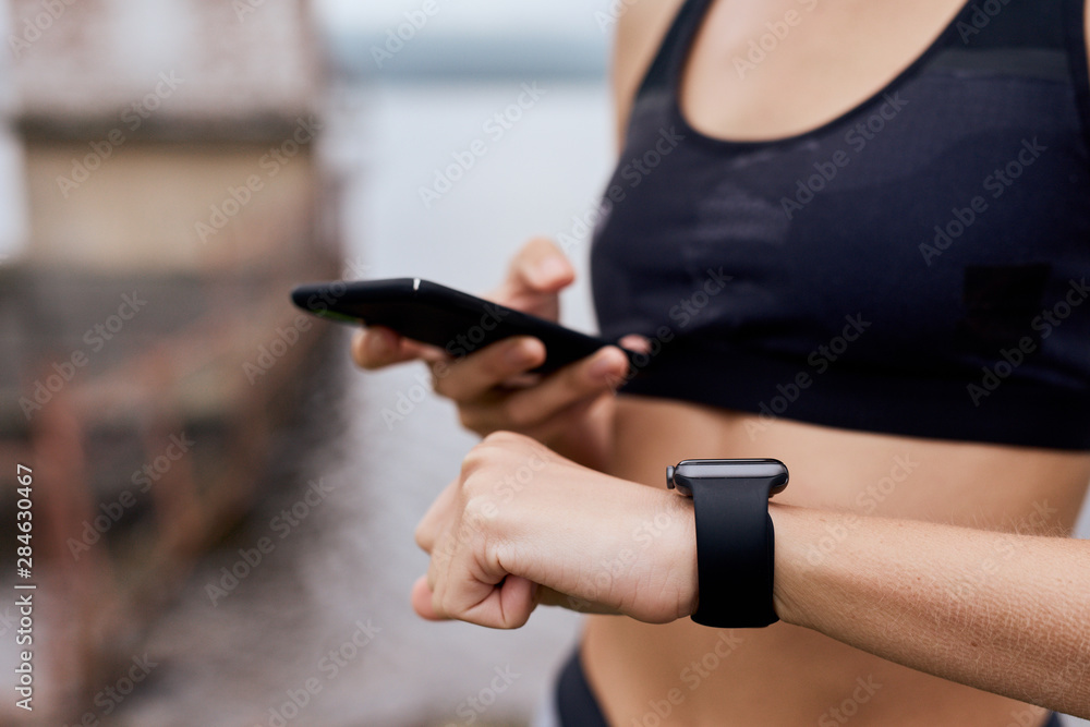 Female hands syncing smart phone and watch putdoor Female hands syncing smart phone and watch putdoor