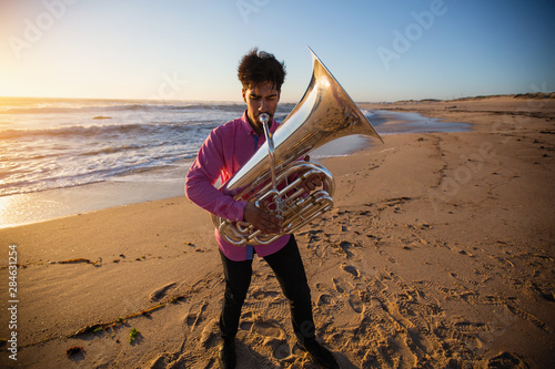 Photography Musician plays a wind instrument standing on the ocean coast.