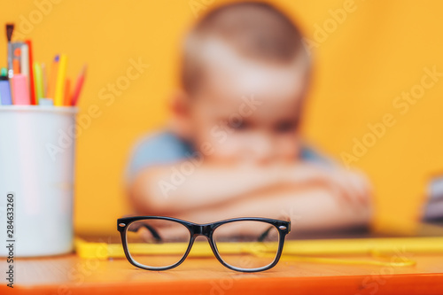 boy sitting ubfocused glasses in focus. Concept problem of ophthalmology correction of myopia. back to school. Selective focus. upset child photo