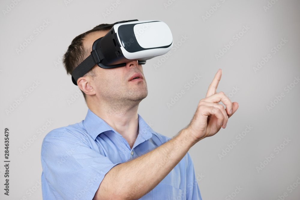 Man wearing virtual reality goggles on grey